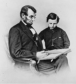 An 1864 Mathew Brady photo depicts President Lincoln reading a book with his youngest son, Tad.